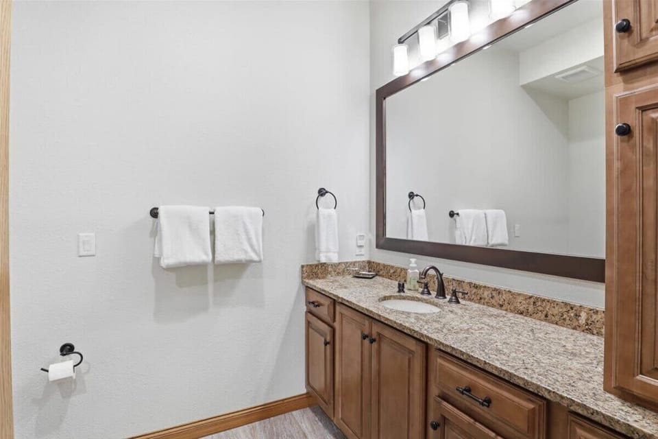 Bright guest bathroom with a spacious vanity, large mirror, and clean, modern finishes.