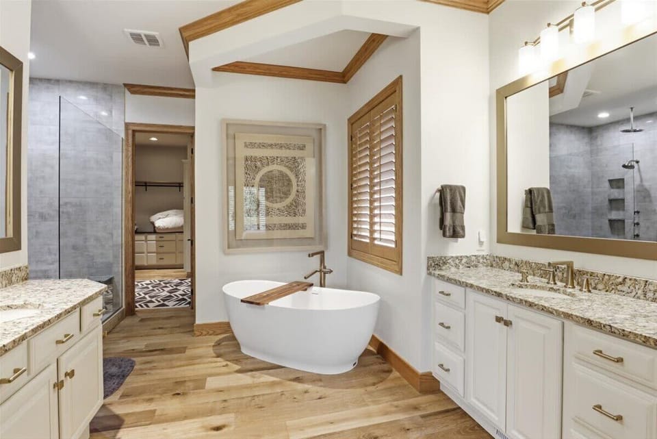 Elegant primary bathroom featuring a soaking tub, double vanity, and walk-in shower for a relaxing vacation experience.
