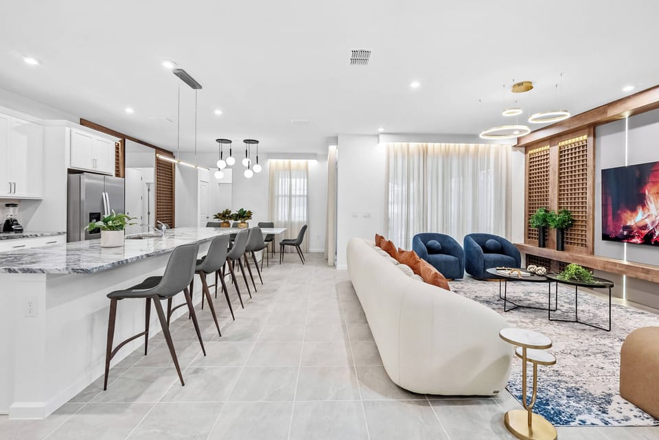 Welcome to a beautifully designed living area with a sleek marble kitchen island and cozy leather armchairs, inviting you to relax. Soft neutral tones and warm lighting create the perfect ambiance to unwind after your adventures.