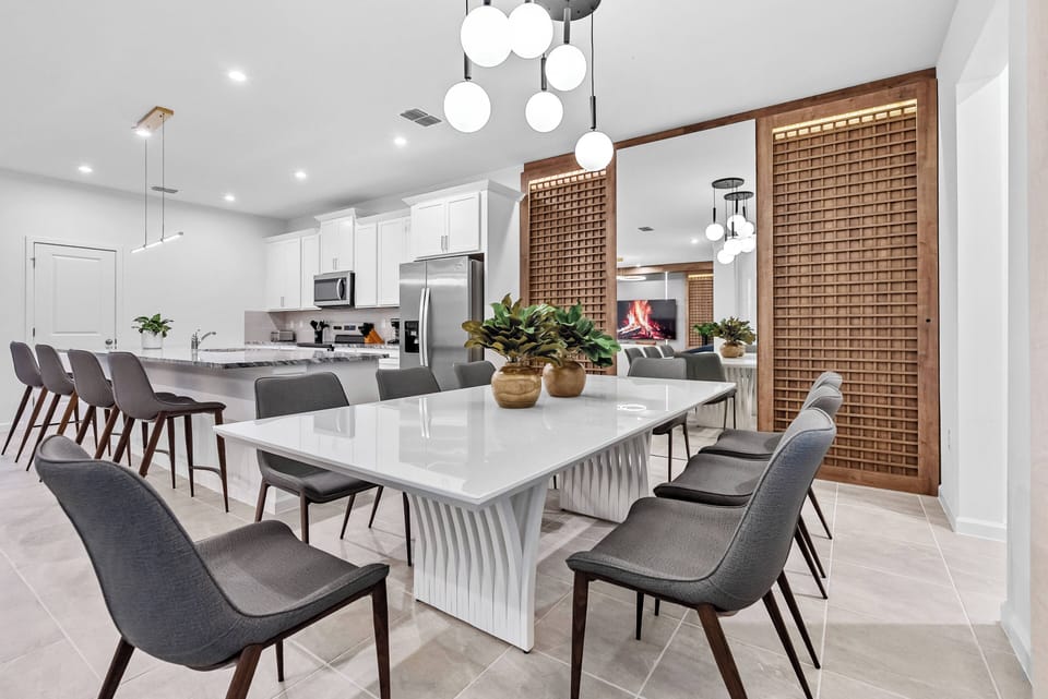 Savor memorable meals at the elegant marble-top dining table with stylish seating. This inviting space features soft lighting and warm wood accents, seamlessly connecting to the modern kitchen, perfect for entertaining guests.