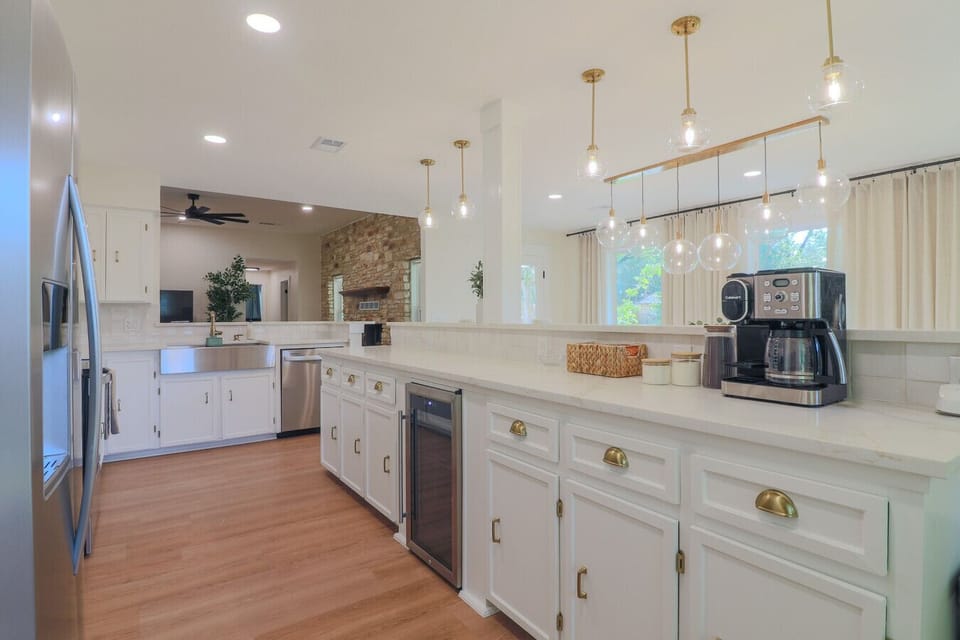 Spacious kitchen island with quartz countertop, built-in wine cooler, dual coffee maker, and gold hardware. Opens directly to the dining area, great for families and groups.