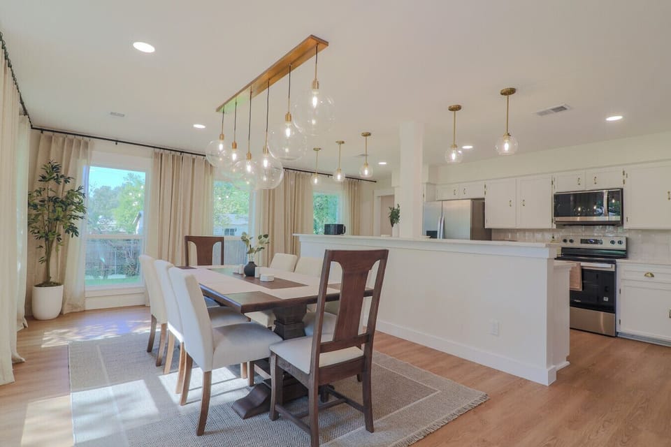 Seats 8 with chandelier lighting, open to a remodeled kitchen with new stainless appliances and floor-to-ceiling curtains. Plenty of room for families to cook and dine comfortably.