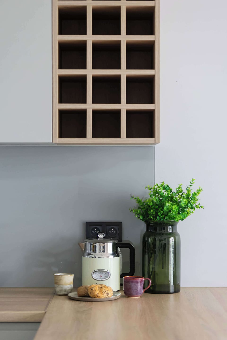 A minimalist wall decoration featuring wooden shelves and small plants. The simple arrangement adds warmth and style to the bright room.