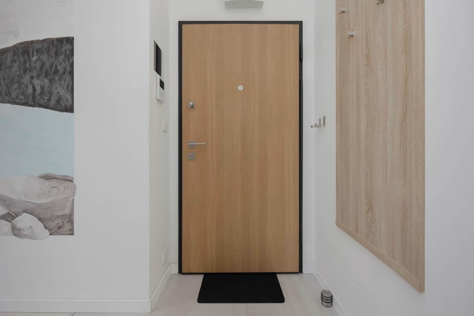 A modern hallway with wooden doors, light walls, and simple finishes. The space is clean, bright, and functional.