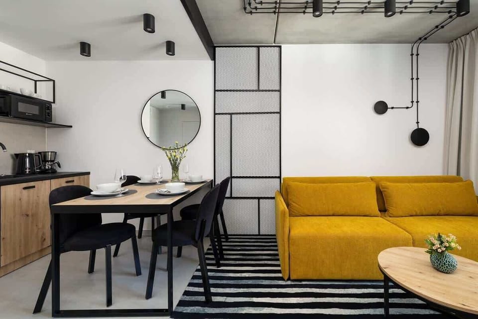 Cozy bedroom with gray bedding and a yellow sofa partially visible behind a sliding partition.

