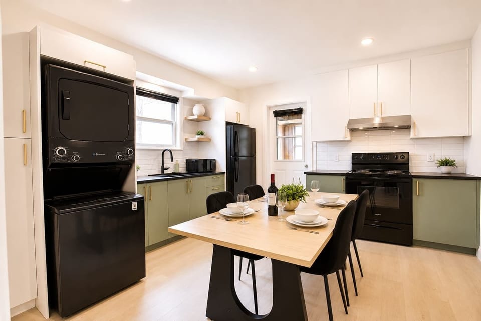 Cuisinez, dînez et profitez. Une cuisine lumineuse avec des armoires couleur sauge, une cuisinière complète, un réfrigérateur et une buanderie intégrée.