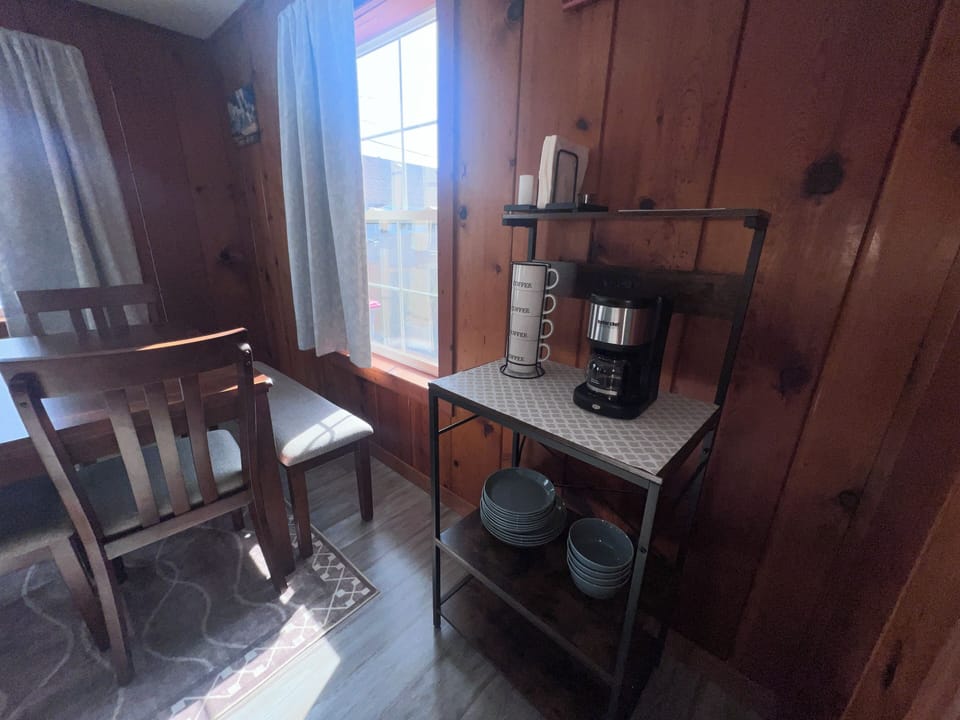 Your cozy kitchenette awaits with everything you need—dishes, coffee maker, and mugs—all nestled in warm wood cabinetry ready for your morning brew.