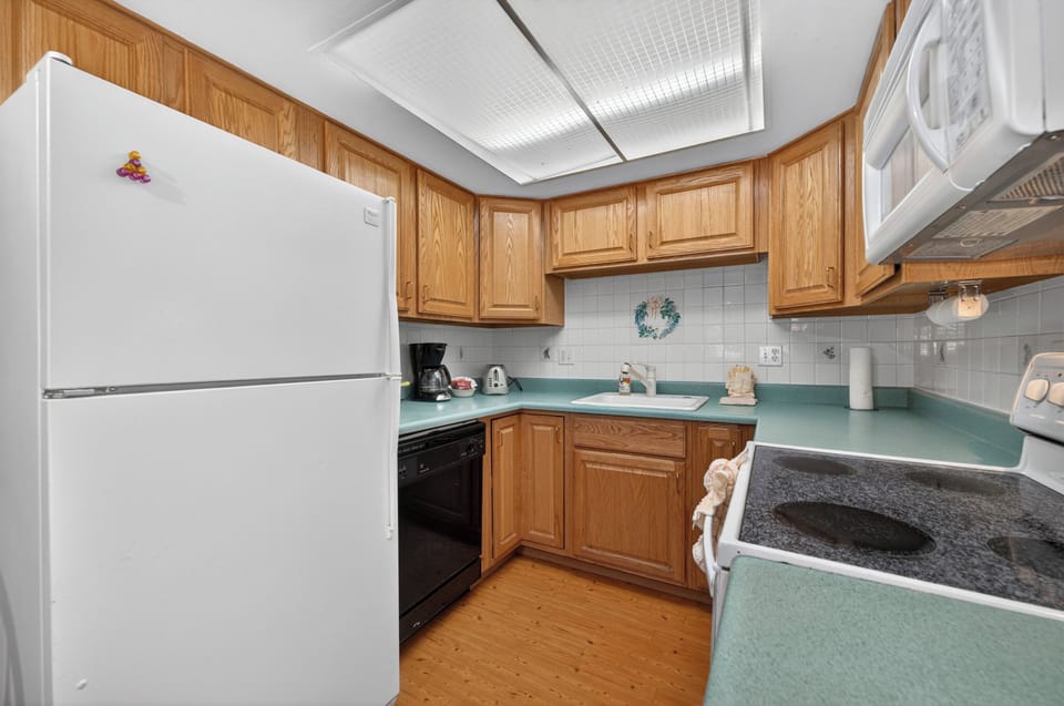 Cook your favorite meals in this fully-equipped kitchen with modern appliances, ample counter space, and warm wood cabinetry that makes you feel right at home.