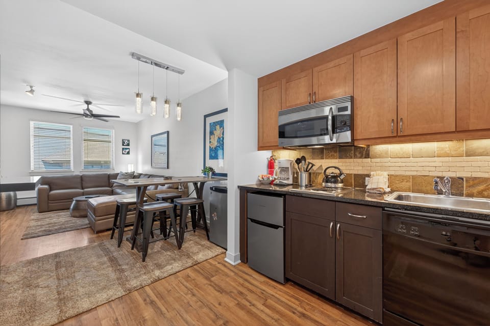Step into your open-concept living space where natural light spills across modern appliances and warm wood accents, creating the perfect backdrop for memorable meals and cozy evenings together.