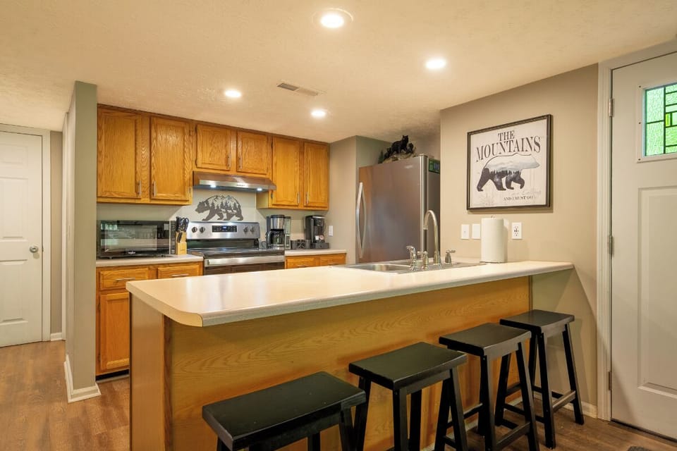 Your fully equipped kitchen features warm wood cabinetry, stainless steel appliances, and a breakfast bar with seating for four—perfect for preparing and enjoying meals together during your mountain getaway.