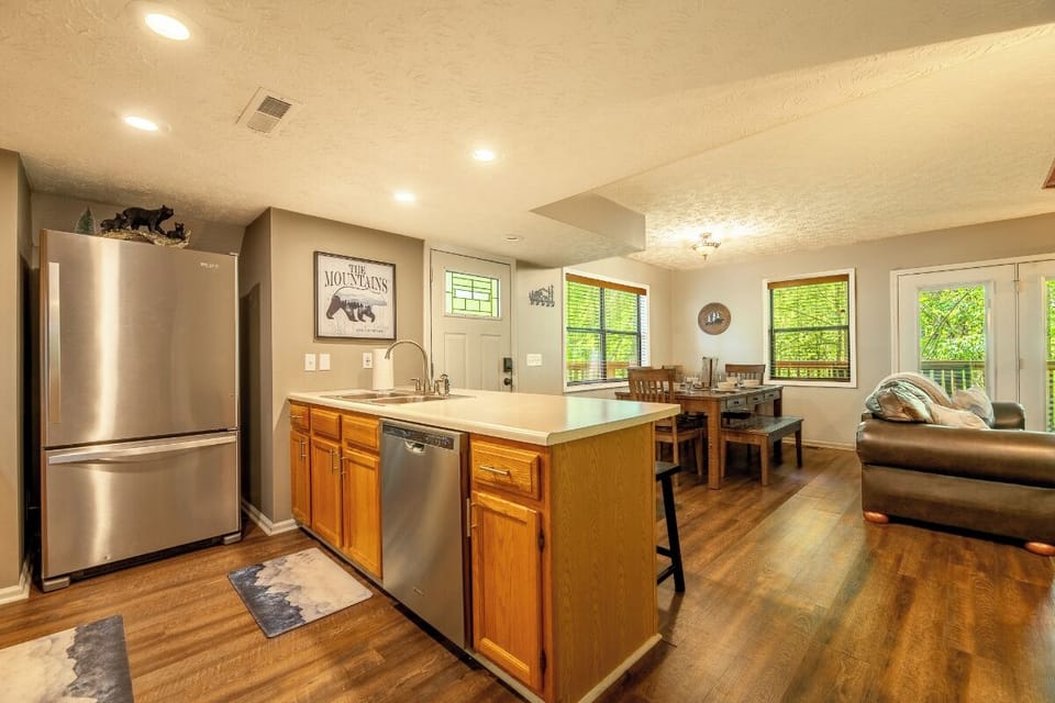 Picture yourself preparing meals in this bright, open kitchen featuring stainless steel appliances, a spacious island with sink, and gleaming countertops. Natural light pours through multiple windows, while the adjacent dining and living areas invite relax