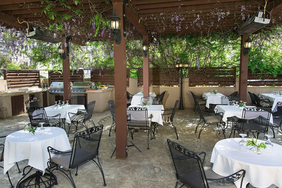 Dine al fresco under the pergola, surrounded by mature trees and garden greenery.