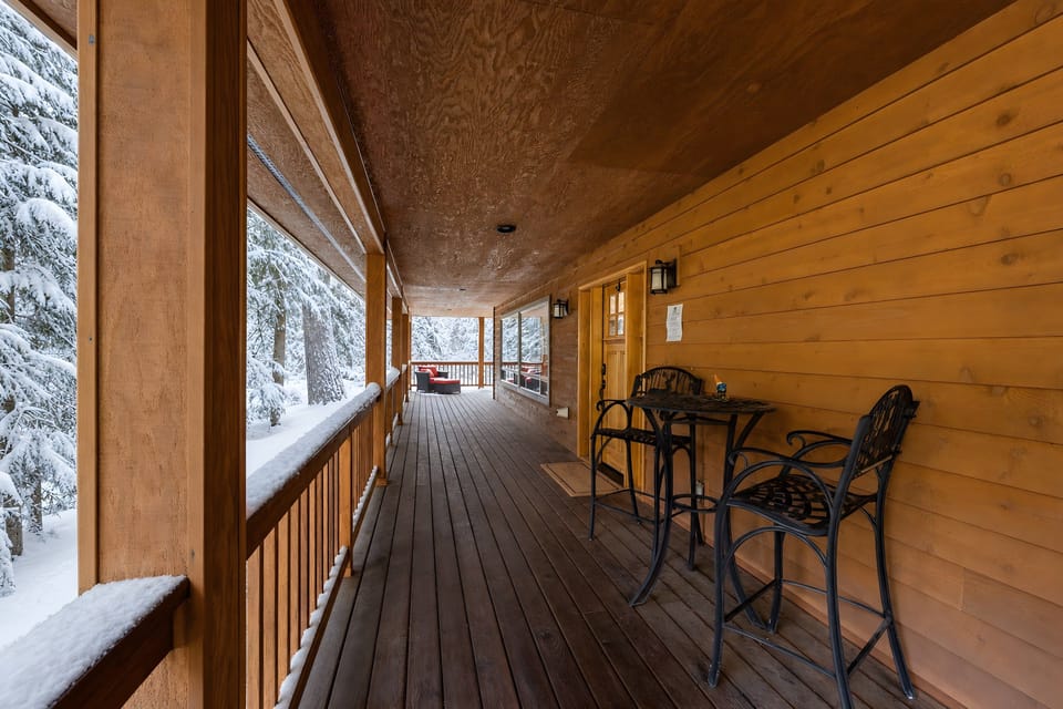 Covered deck with table and chairs beside the house.