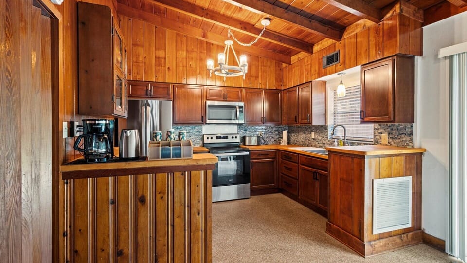 The rustic kitchen is well equipped with cooking essentials, coffee maker, oven, stove, full size refrigerator and freezer, microwave, and toaster.