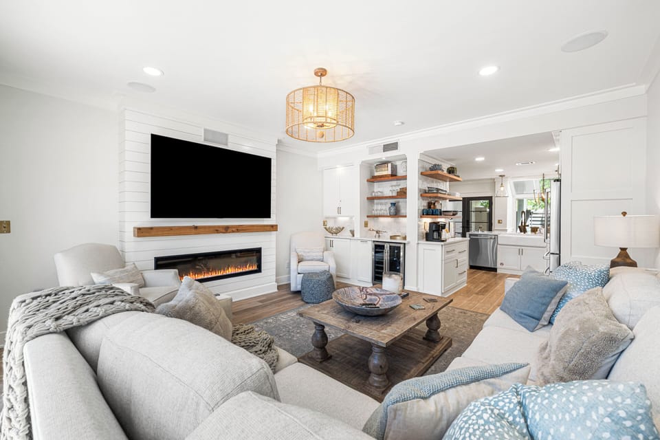 Open-concept living area with a fireplace and TV. You can relax on the large sofa while watching a show or easily grab a drink.