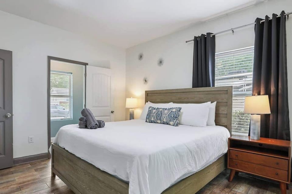 Bedroom with a king bed, bedside lamps, and blackout curtains.