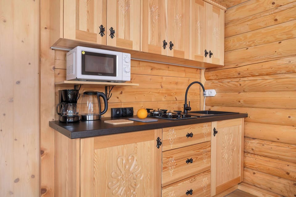 A detail of the kitchenette with a microwave, coffee maker, and kettle on the countertop. The cabinets are adorned with carvings that highlight the high-quality finish.
