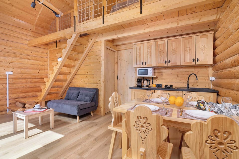 A wide shot of the ground floor, including the kitchenette, dining area, and stairs leading upstairs. The interior layout is open and well-thought-out, encouraging time spent together.