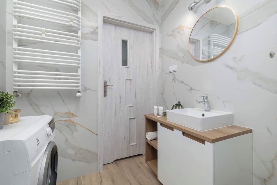 This view of the bathroom highlights the large mirror and the ladder-style towel radiator. The clean white finishes make the space feel hygienic and bright.