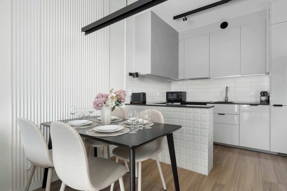 View from the living area toward the kitchenette and dining area, with white chairs around the dining table.