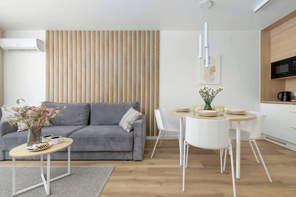A bright, welcoming space featuring a plush grey sofa, a wooden dining table, and a feature wall. Ideal for contemporary living.