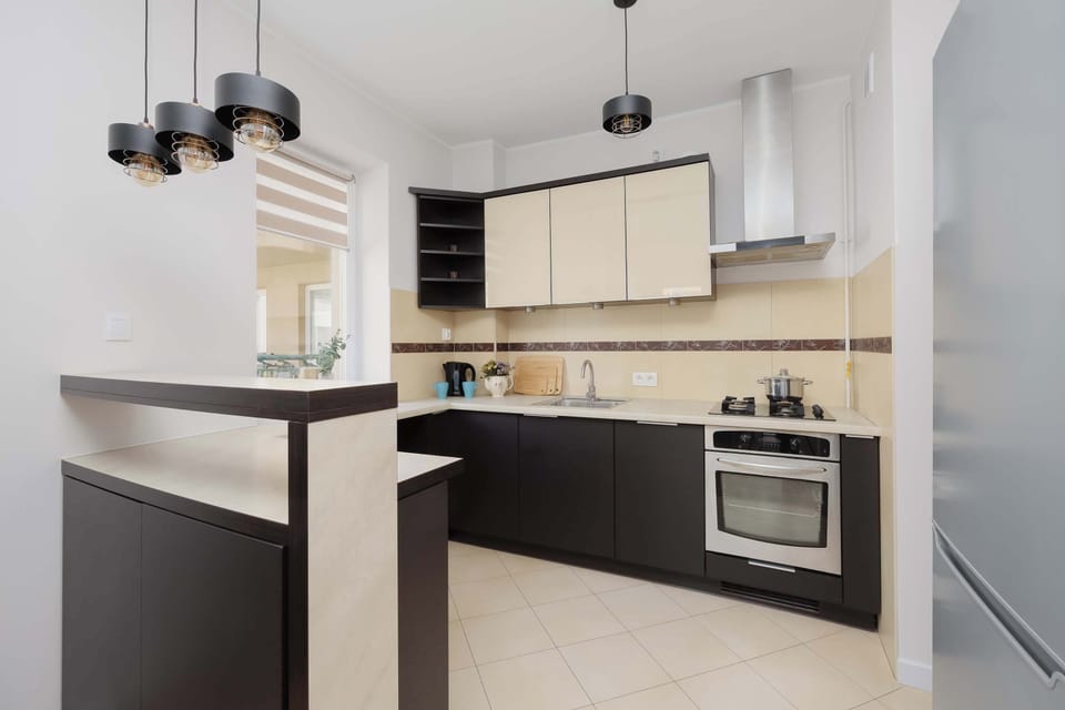 An L-shaped kitchenette with a built-in gas stove, oven, and stainless steel range hood.