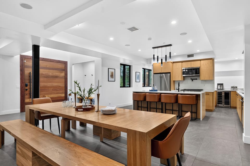 Open dining and living area with warm wood accents, leather seating, and seamless access to the covered outdoor lounge.