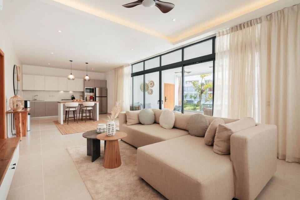 Bright, open living room with a spacious sofa, dining area, and fully equipped kitchen.