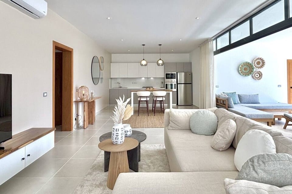 Bright open-plan living area with a fully equipped kitchen, comfortable seating, and direct access to the balcony — perfect for relaxing after a day at the beach.