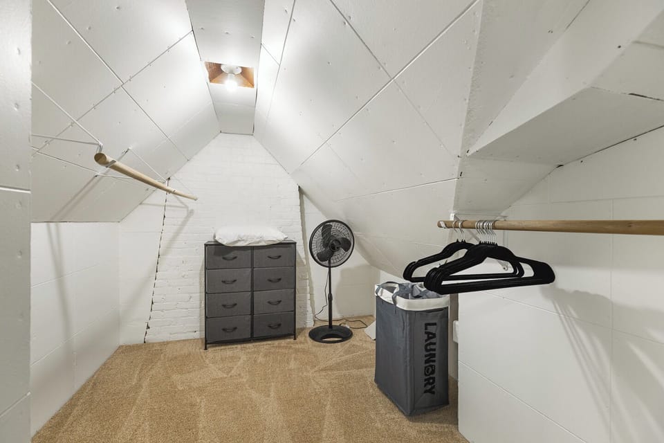 Spacious walk-in closet with dual rods, dresser, hangers, and hamper.