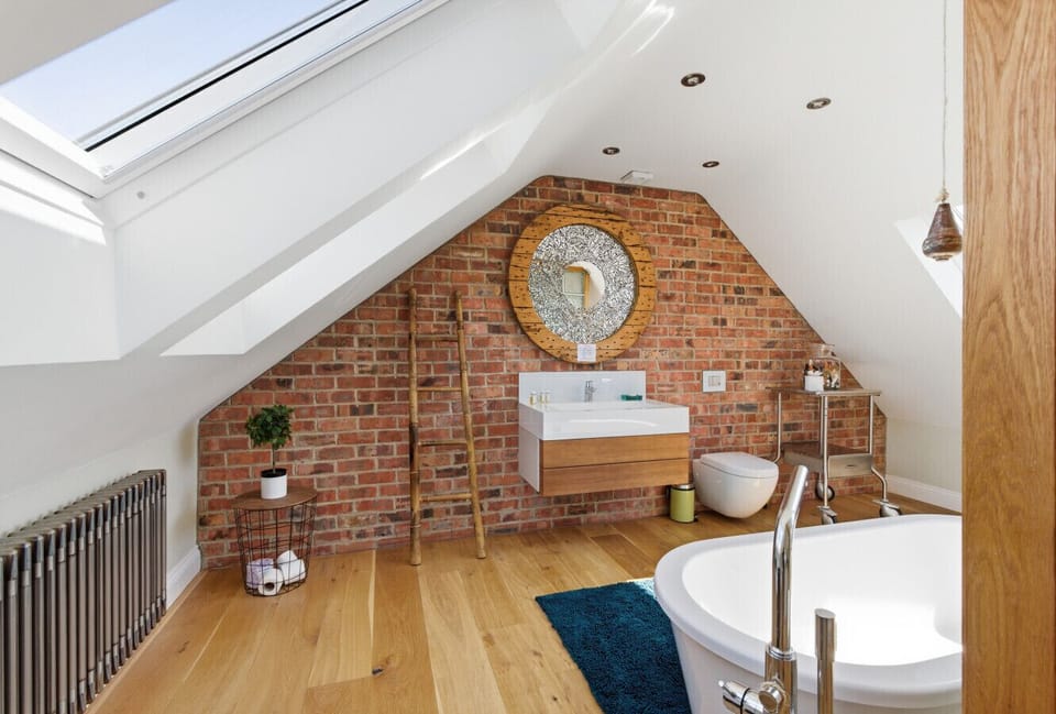 Loft master bathroom with skylights, exposed brick and freestanding bath.