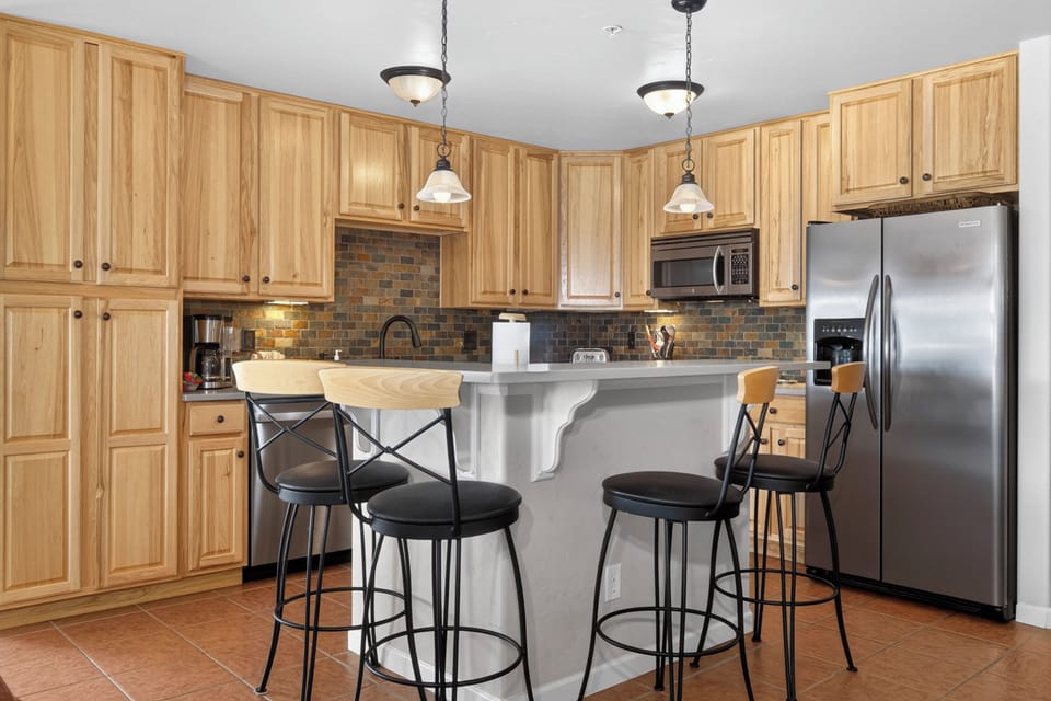 Your fully equipped kitchen invites culinary adventures with warm wood cabinets, modern appliances, and a breakfast bar perfect for morning coffee.