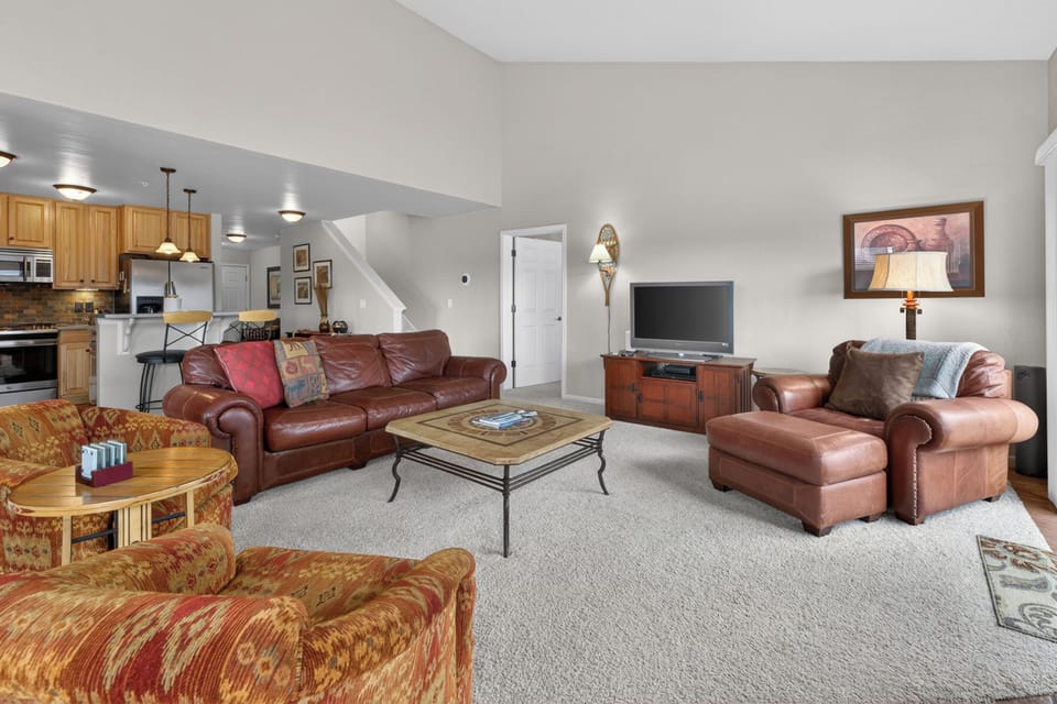 Sink into plush leather sofas in your spacious living room, where warm wood tones and soft lighting create the perfect retreat.