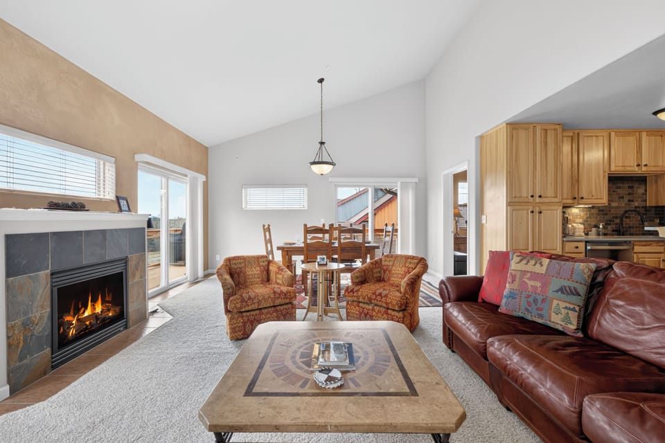 Cozy up in this stunning open-concept living space where warm flames dance in your stone fireplace while you relax on leather sofas.
