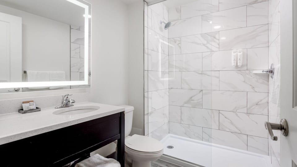 Refresh under a hot shower in a spotless bath.