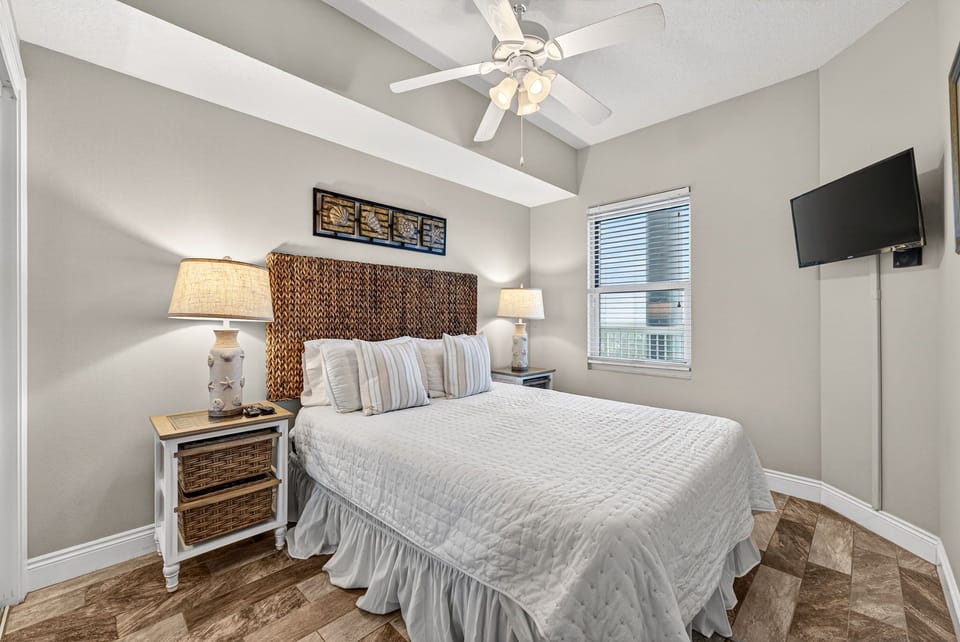 Your serene bedroom retreat features a plush bed, vaulted ceilings with a fan, soft lighting, and a flat-screen TV for your comfort.