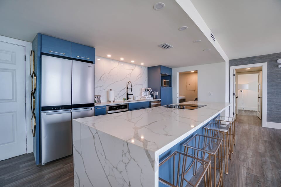 Your stylish kitchen features sleek marble countertops, modern navy cabinetry, and stainless-steel appliances—perfect for preparing meals and gathering with loved ones during your stay.