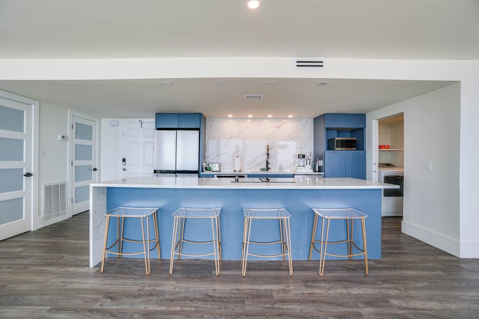 Gather around your modern kitchen island with sleek blue cabinetry, white marble backsplash, and plenty of seating for cooking and conversation.