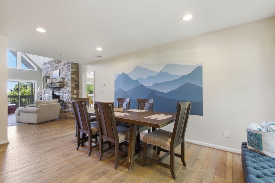 Open dining space with mountain mural, stone fireplace, and natural light