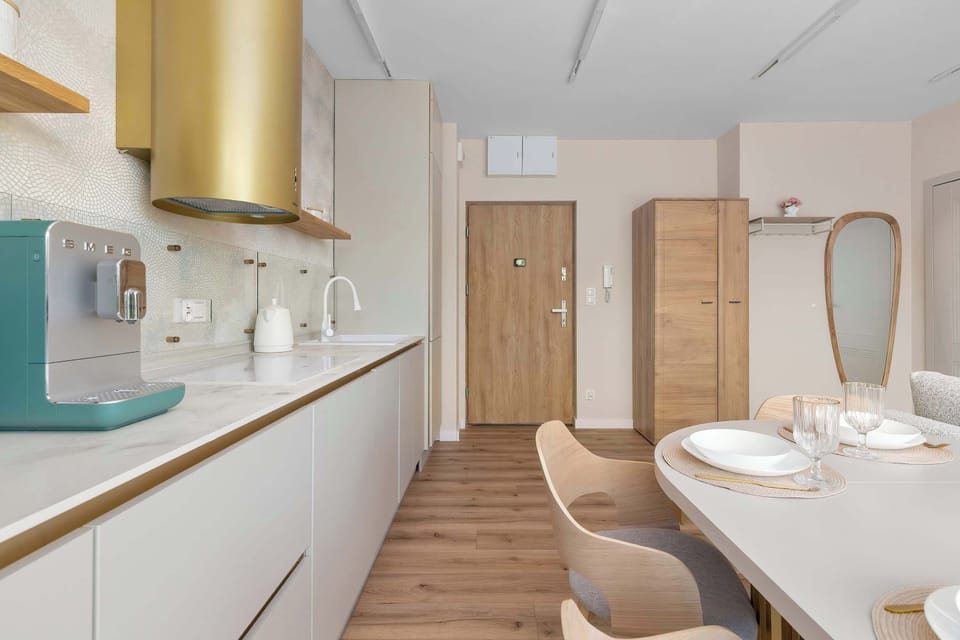 The entrance area shows a light wood door and a matching tall wardrobe for storage. A small mirror and a dining chair are visible, maintaining the apartment's consistent neutral color palette.