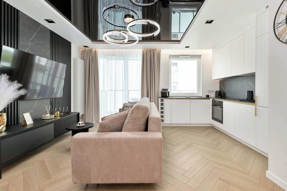 This wide-angle perspective captures the flow between the kitchen and the living area. The consistent use of light wood flooring and white walls creates a cohesive, airy atmosphere.