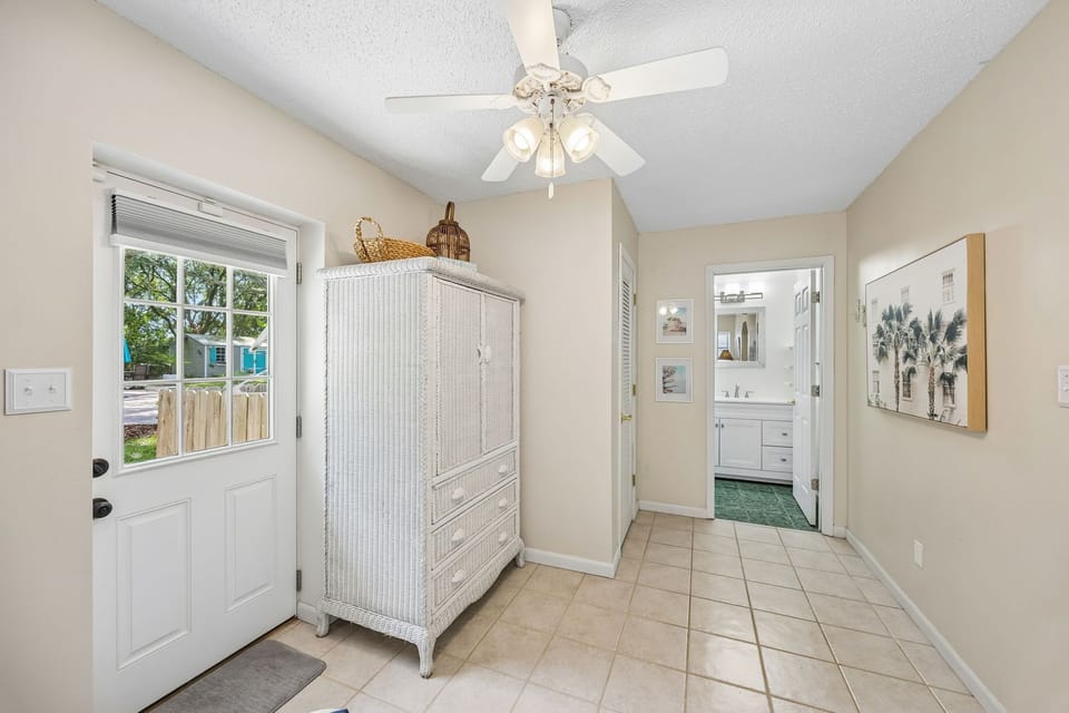 Step into your bright entryway where coastal charm greets you with breezy decor, practical tile flooring, and a welcoming glimpse of the relaxing spaces beyond.