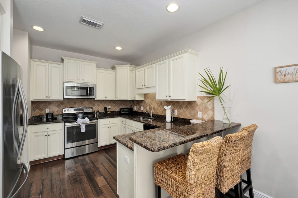 Your home away from home features a fully equipped kitchen with modern appliances, granite countertops, and a breakfast bar where you can enjoy morning coffee or casual meals.