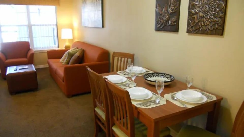 Dining area with table set for four and orange chairs.