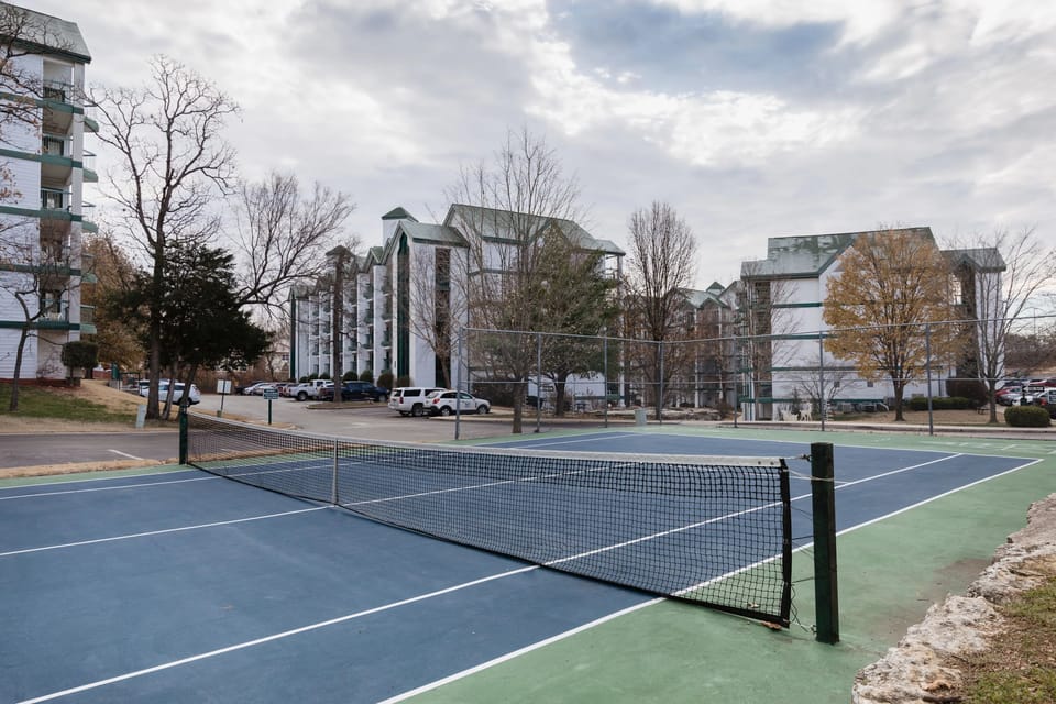 Outdoor tennis court surrounded by resort buildings.
