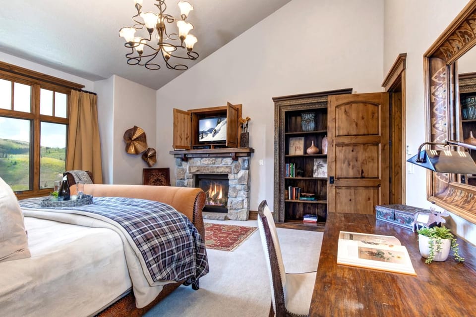 The main-level King suite blends comfort and elegance with a fireplace, writing desk, and mountain light.
