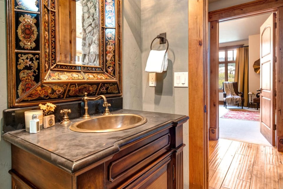 This elegant half bath features ornate wood accents, granite vanity, and mountain lodge flair.