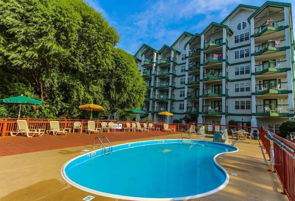 Outdoor pool with sun loungers and lush resort surroundings.