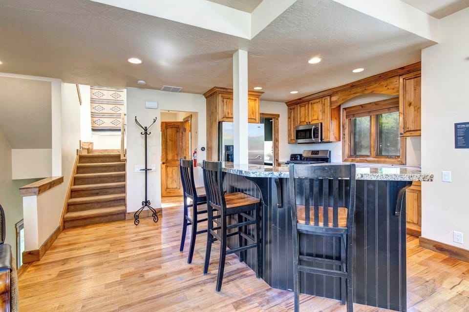 Open kitchen with breakfast bar, wooden flooring, and cozy living space.