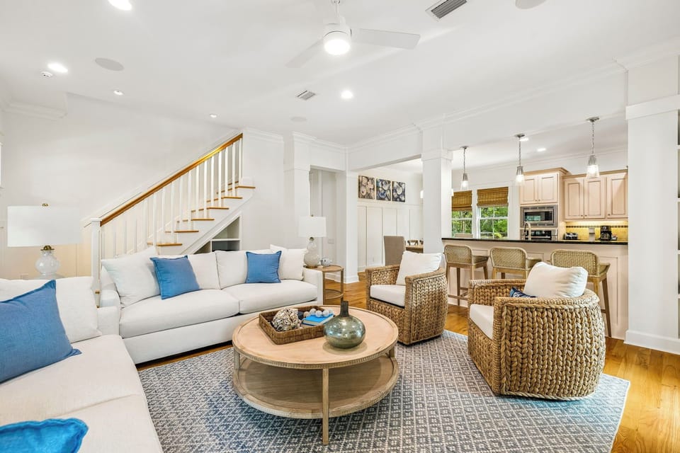 Sink into plush sofas and textured wicker chairs in your open-concept living space, where natural light streams through the kitchen and coastal-chic décor invites your perfect getaway.